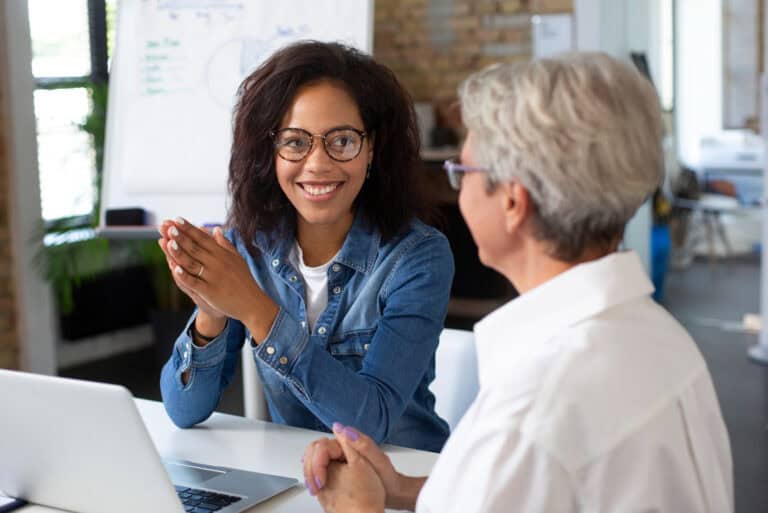 Diverse women discussing mentorship program strategies in an office setting.
