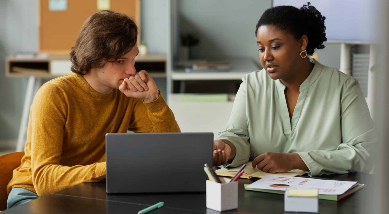 Two professionals collaborating on mentorship software at a desk.